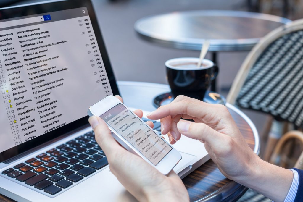 Someone checking emails on an Iphone and computer